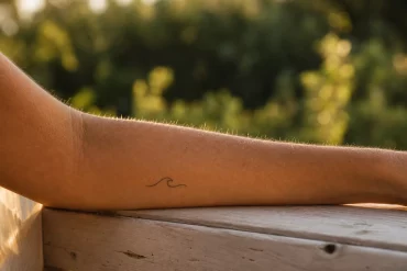 Minimalistisches Wellen-Tattoo am Unterarm im Freien